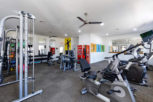 A gym with a variety of equipment including treadmills, weights, and exercise machines.