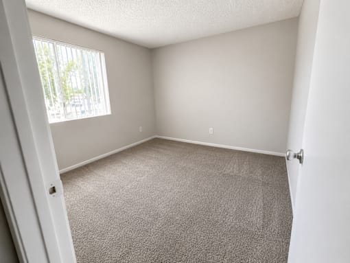 A room with a carpeted floor and a window with blinds.