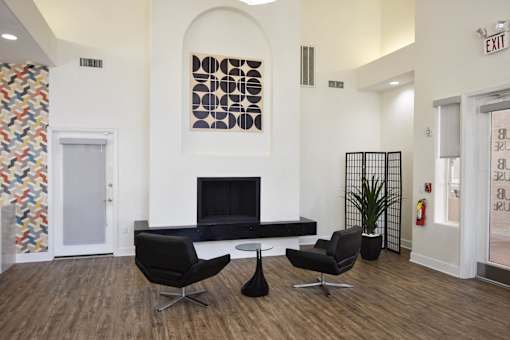 A black chair sits in front of a fireplace in a white room.