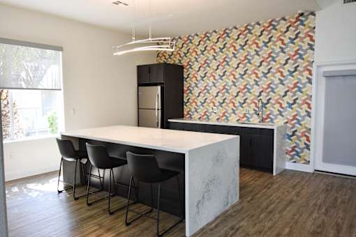 A kitchen with a marble countertop and a patterned wallpaper.