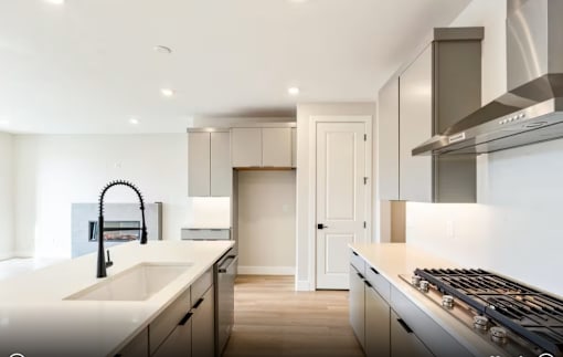 A modern kitchen with a white countertop and stainless steel appliances.