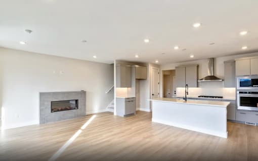 A modern kitchen with a fireplace and wooden floors.