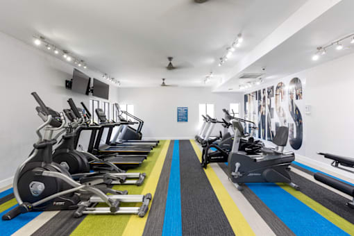 A gym with a row of stationary bikes.