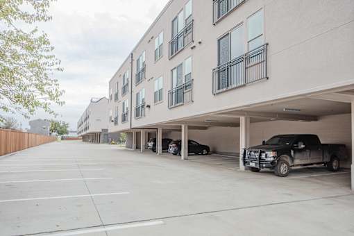 Covered parking garage with residential units above at Avion at West Lemmon Apartments, Dallas, Texas