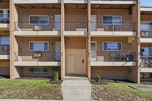 Apartment building with a small front yard and a walkway leading to the entrance.