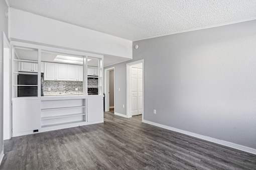 A spacious, empty room with a kitchen area to the left and a door to the right.