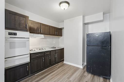 A kitchen with dark brown cabinets and a black refrigerator.