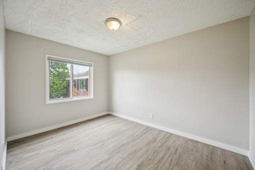 A room with a window and wooden flooring.