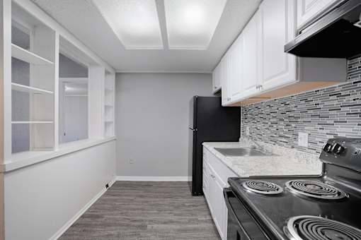 A kitchen with a black stove top oven and white cabinets.