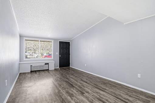 A room with a black door and a window with a view of a street.