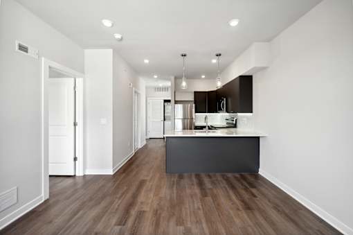 A modern kitchen with a dark wood floor and white walls.