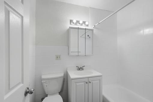 A white bathroom with a toilet, sink, and medicine cabinet.
