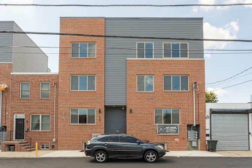 A black car is parked in front of a brick building.