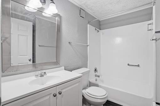 A white bathroom with a toilet, sink, and bathtub.