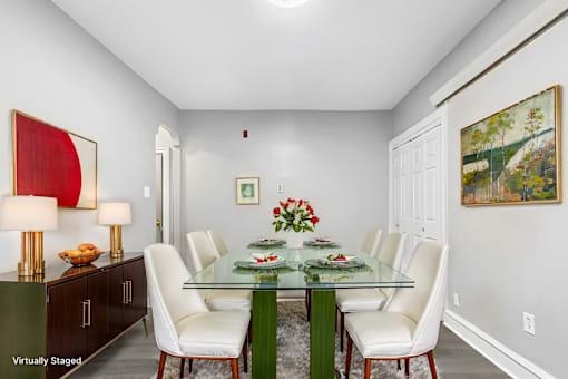 A dining room with a glass table and white chairs.