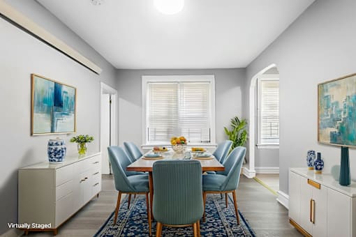A dining room with a table set for six and a blue rug on the floor.