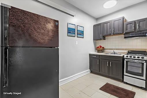 A kitchen with a black refrigerator and a stove top oven.