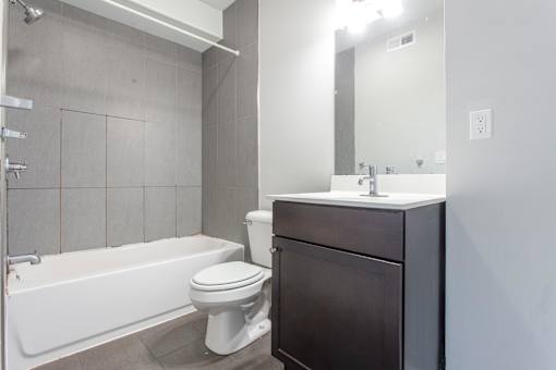 A white toilet sits next to a white bathtub in a bathroom.