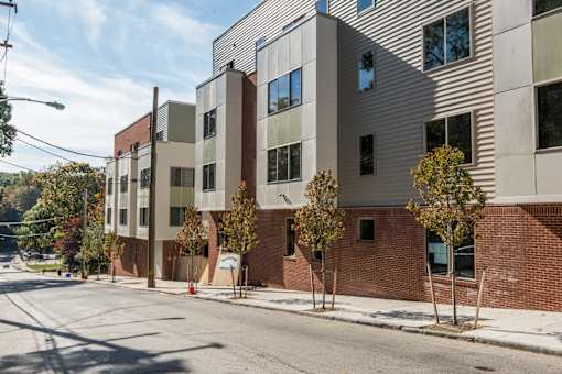 A street view of a modern building with a mix of brick and panel facade.