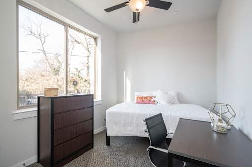A bedroom with a bed, dresser, and desk.