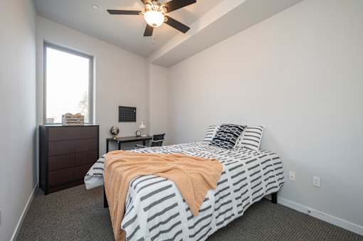 A bedroom with a bed, nightstand, and window.