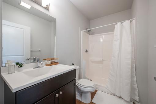 A white bathroom with a sink, toilet, and shower.