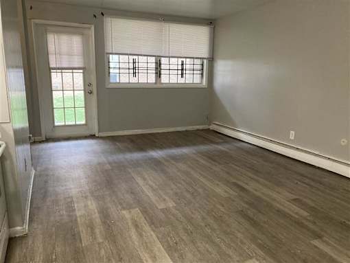 A room with wooden flooring and a window with blinds.