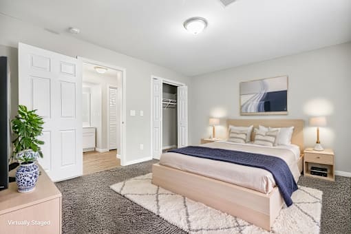 A bedroom with a bed, nightstands, and a plant.