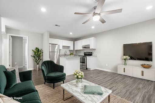 A living room with a green couch, a black chair, and a white coffee table.