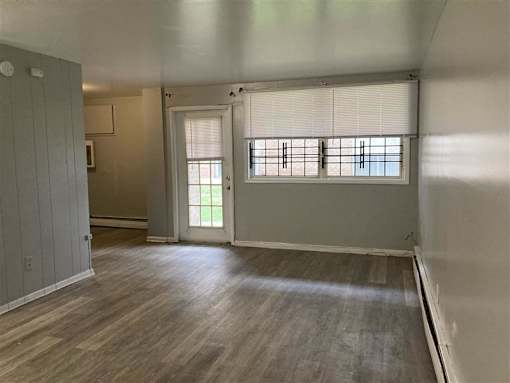 A room with wooden flooring and a window with blinds.