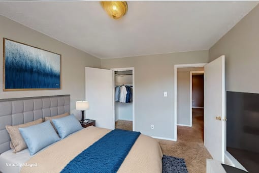 A bedroom with a bed, a lamp, and a painting on the wall.