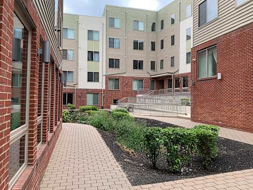 A brick building with a walkway and bushes in front.