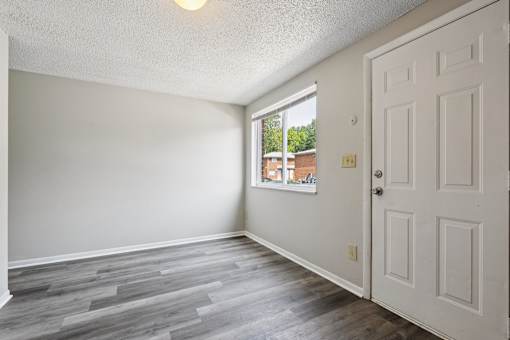 A room with a white door and a window showing a view of a building outside.