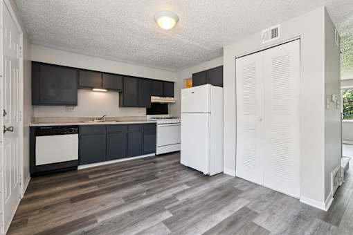 A kitchen with a white fridge and black cabinets.