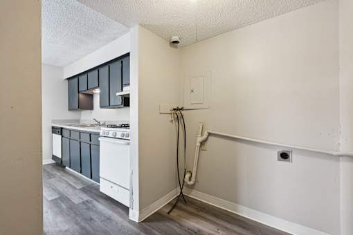 A kitchen with a stove top oven and a wall with a pipe running along it.
