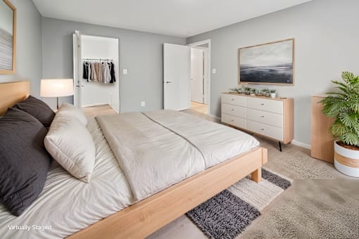 A bedroom with a large bed, a dresser, and a plant.
