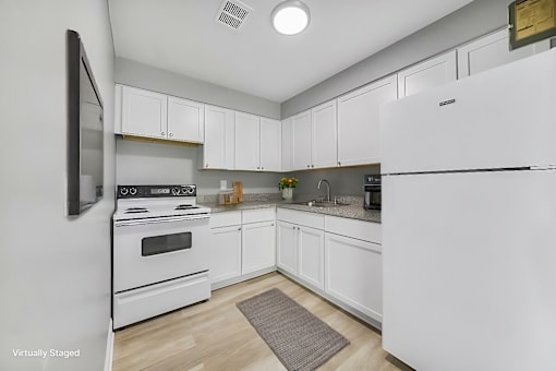 A kitchen with white appliances and cabinets.