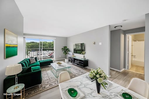 A living room with a green couch and a glass table.