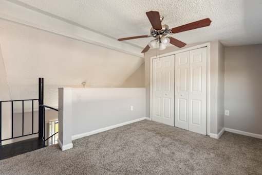 A room with a ceiling fan and a staircase.