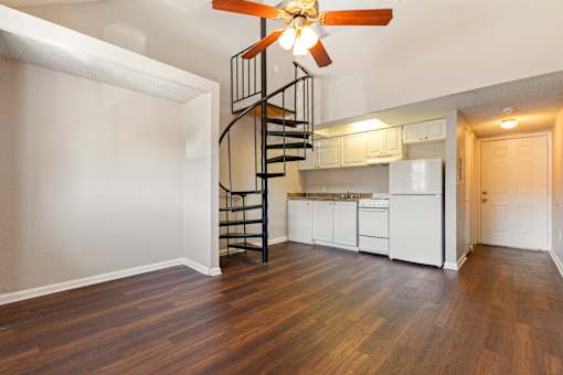A living room with a spiral staircase and a ceiling fan.