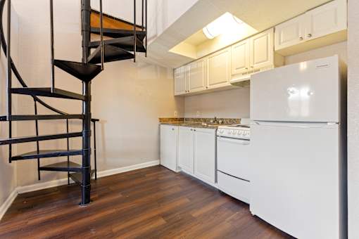 A kitchen with a white fridge and wooden floors.