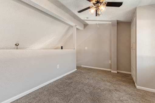 A room with a ceiling fan and carpeted floor.
