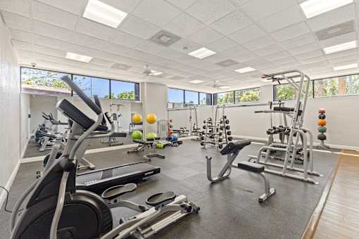 A gym with a variety of equipment including treadmills, weights, and exercise machines.