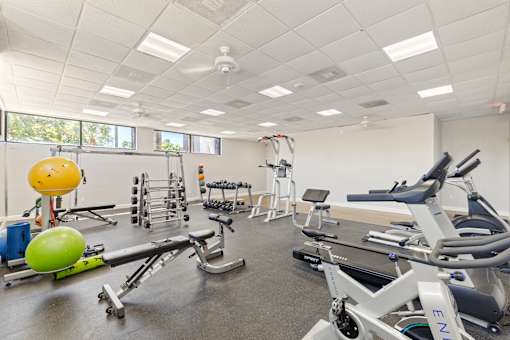 A gym with a variety of equipment including a leg press machine, a bench press, and a rowing machine.