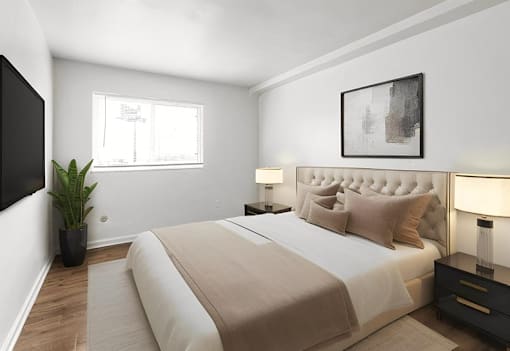 A bedroom with a large bed, a plant, and a painting on the wall.