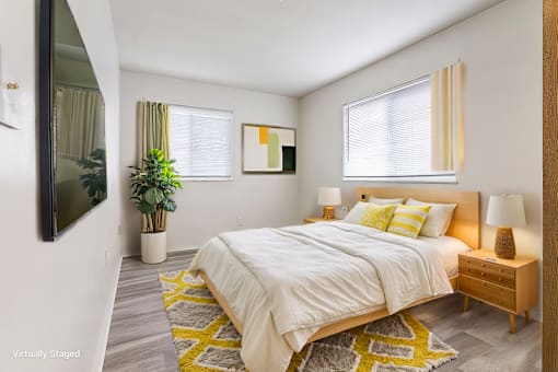 A bedroom with a bed, nightstand, and a plant.