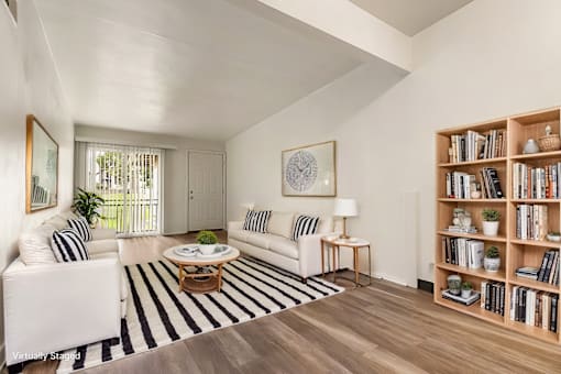 A living room with a white couch, a coffee table, and a bookshelf.