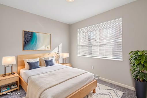 A bedroom with a large bed, a painting on the wall, and a potted plant.