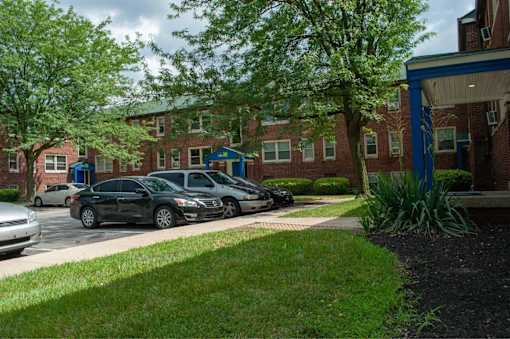 A black car is parked in front of a brick building.