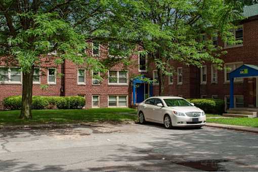 A white car is parked in front of a red brick building.